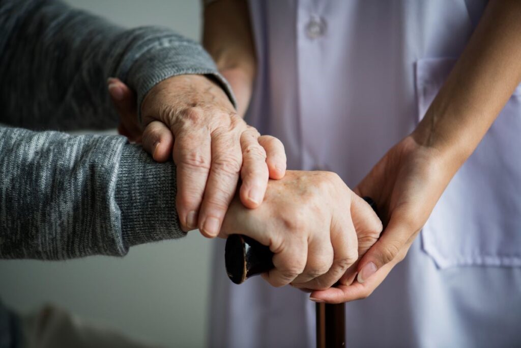 A nurse gently holds the hand of an elderly person, symbolizing compassion and caregiving in a healthcare setting.