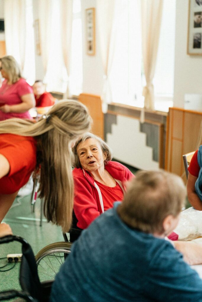 A woman assists an elderly woman at a table.