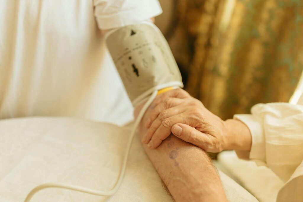 A person demonstrates a blood pressure monitor, focusing on the care of chronic conditions among the elderly.