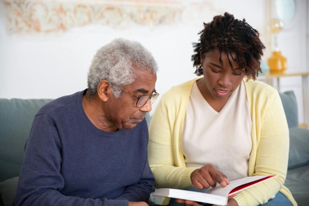 A caregiver with an older man, reading a list together, sharing a moment of learning and connection.