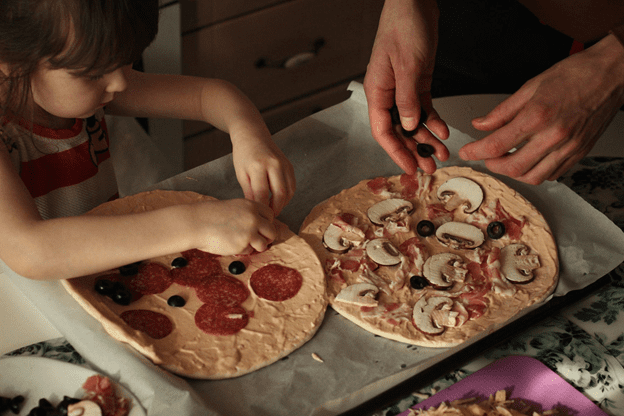 A family cooking a homemade pizza together.